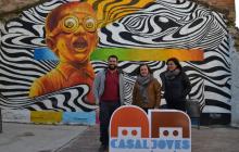 La regidora Montserrat Flores (centre) i dues persones responsables del Casal de Joves davant un mural de 